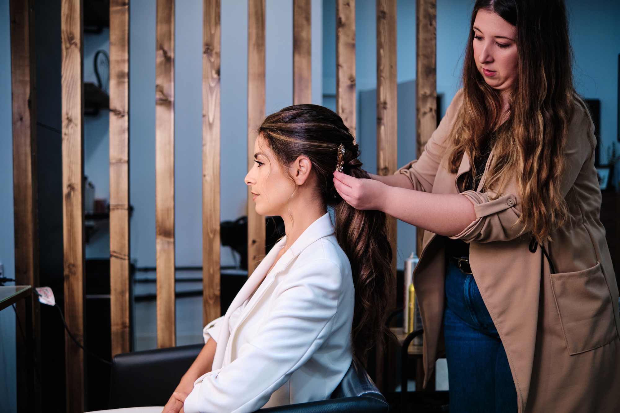 Hairstylist doing a hairstyle for a bride for her wedding day at the hair salon.